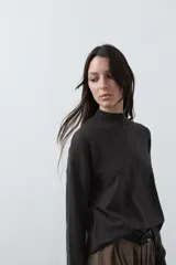 Polera de tejido de punto color gris oscuro, con cuello alto y diseño de rombos en relieve en el frente. Presenta un calce relajado con terminaciones en rib en cuello, puños y ruedo.