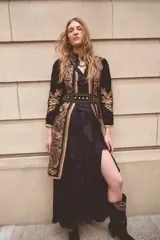 Vestido largo negro de estilo bohemio, con escote en V, volados en la parte frontal y una abertura lateral pronunciada en la falda.