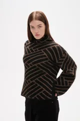 Sweater de tejido jacquard con diseño geométrico de líneas entrelazadas en tonos negro y marrón. Presenta cuello alto, mangas largas con terminación holgada y un corte recto.