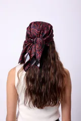 Pañuelo cuadrado de seda con estampado repetitivo de un diseño abstracto en rojo sobre fondo negro.