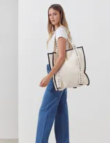 Bolso tipo tote bag de lienzo color crudo, con vivos en cuerina negra y estampado vertical con el texto "LA OPERA".