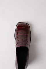 Mocasín de cuero con textura de reptil en color bordó, con puntera cuadrada y taco bloque bajo de color negro.