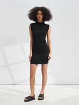 Vestido corto negro de corte ajustado, sin mangas, con cuello alto y frunces laterales.