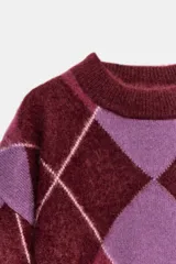 Jersey de punto de lana con diseño de rombos en tonos bordó y lila. Presenta cuello redondo, manga larga con puños ajustados y corte holgado.