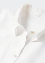 Camisa blanca de lino con cuello clásico, manga corta, corte oversize, cierre frontal con botones y bolsillo de parche en el pecho.