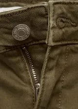 Pantalón tipo jeans de tiro medio en color verde oliva, con diseño acampanado y bajo deshilachado. Presenta dos bolsillos de parche en la parte delantera, cierre de cremallera y botón, y trabillas para cinturón.