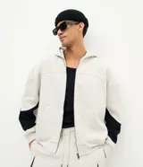 Campera con capucha de felpa en color gris melange, con cierre frontal, bolsillos tipo canguro y paneles negros en las mangas.