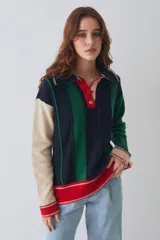 Buzo estilo polo de lambswool con diseño color block a rayas verticales en tonos beige, marrón y rojo. Presenta cuello camisero, cartera frontal con botones, mangas largas con coderas y tajos laterales en el ruedo.