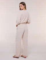 Pantalón pull-on de color beige con caída fluida, cintura elastizada fruncida, bolsillos laterales funcionales y pierna amplia de corte wide leg.