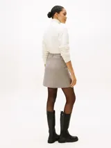 Mini falda de corte recto con estampado de cuadros en tonos beige y marrón. Presenta un diseño clásico con cierre frontal y estructura definida.