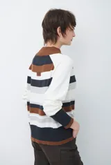 Polera de tejido de punto con diseño de rayas horizontales en tonos beige, marrón, gris y negro. Presenta cuello redondo y mangas largas con puños en contraste.
