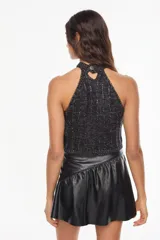 Top de punto estilo halter, color crudo, con cuello alto ajustado, diseño sin mangas y corte corto.