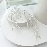 Aros colgantes largos de plata 950, con diseño abstracto de líneas curvas y terminación irregular.