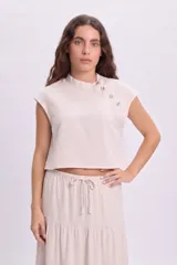 Blusa sin mangas de color crudo, con cuello mao y cierre lateral de botones decorativos.