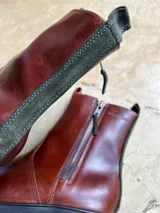 Botas de cuero marrón con suela de goma track y doble cierre lateral con tiradores de gamuza. Cuenta con presilla trasera y detalle de panel posterior en gamuza a contratono.