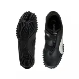 Championes Puma modelo Mostro Perforated, de diseño bajo con exterior de cuero perforado en color blanco y detalles en negro. Presenta una suela distintiva con relieve de tachones y cierre de velcro en el empeine.