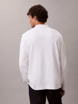 Chomba de manga larga Calvin Klein confeccionada en algodón interlock, con cuello clásico, cartera con botones y logo bordado en el pecho.