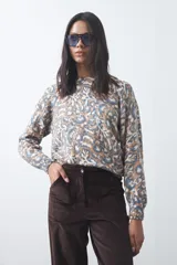 Sweater de punto con diseño de estampado animal print abstracto en tonos tierra y azul claro. Presenta cuello redondo a la base, mangas largas levemente amplias y terminaciones acanaladas en puños y ruedo.