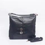 Cartera tipo bolso de hombro color negro, confeccionada en material texturizado con detalles de correas decorativas y hebillas metálicas doradas en el frente. Cuenta con asa superior fija y correa larga ajustable y extraíble.