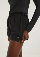 Short deportivo de corte runner, con cintura elástica y pequeña abertura lateral en el ruedo. Presenta un logo reflectante en la parte inferior.