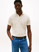 Chomba Tommy Hilfiger color crema con estampado de hojas en tono beige, cuello clásico, solapa de dos botones, corte regular y logo bordado en el pecho.