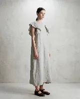 Vestido midi de lino con corte holgado, cuello redondo, volados en los hombros y bolsillos delanteros aplicados.