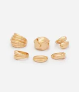 Kit de seis anillos de metal con baño dorado, compuesto por un modelo bold liso, cinco texturizados y uno con diseño de gota.