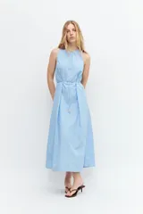 Maxi vestido celeste con rayas verticales blancas, cuello halter y lazo ajustable en la cintura.