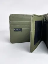Billetera de hombre color negro, con diseño combinado de textura lisa y texturizada en el lateral, con el logo de la marca Rusty Co grabado.