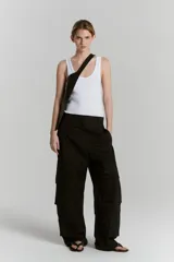 Pantalón negro de gabardina de algodón, corte ancho, con cintura sastrera, bolsillos delanteros con pinzas, bolsillos 3D plaque con tapa y pestaña en el recorte de la pierna.