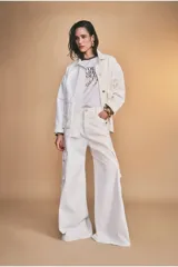 Chaqueta color blanco hueso, de corte recto, con cuello camisero, cierre frontal con botones y bolsillos de parche en el pecho.