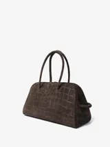 Bolso de mano Jacquemus modelo Le Turismo, confeccionado en cuero con textura de efecto cocodrilo. Presenta un diseño estructurado con asas superiores, cierre de cremallera y un detalle de nudo decorativo en uno de los laterales.