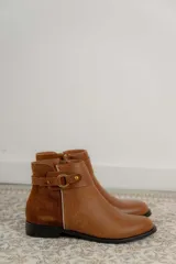 Botas cortas de cuero negro con paneles traseros de gamuza, cierre lateral y detalle de correa con hebilla metálica en el tobillo.