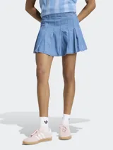 Minifalda plisada de denim azul, de talle medio, con diseño inspirado en la estética futbolística retro y cierre de cremallera.