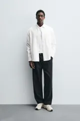 Pantalón de corte relaxed fit confeccionado en mezcla de algodón y modal. Presenta cintura con pliegues frontales, bolsillos laterales y bolsillos traseros con solapa. Cierre frontal con cremallera y botón.