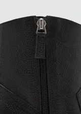 Botín de cuero vacuno color negro, con diseño de estilo western, punta fina y tacón bloque de 6,5 cm. Cuenta con cierre de cremallera lateral.