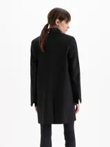 Saco sastrero estructurado de color negro, con largo hasta la rodilla, cuello con solapa de pico ancha y cierre frontal de dos botones. Cuenta con bolsillos con solapa y está completamente forrado.