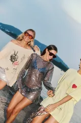 Vestido corto de lentejuelas negras translúcidas con mangas largas.