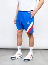 Bermuda de felpa color azul marino, con cortes laterales en blanco y rojo. Incluye el escudo del Club Nacional de Football en una pierna y el logo de Umbro en la otra.