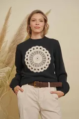 Buzo de punto color negro con cuello redondo, mangas largas y detalle de mandala tejido en color crema en el frente.