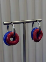 Aros tipo argolla de plata 925 con dijes circulares de vidrio en colores azul y rojo.