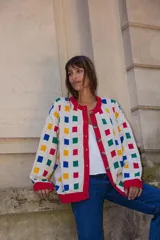 Cardigan de punto color crudo con estampado de cuadrados multicolores, cuello redondo, cierre frontal con botones y terminaciones en tejido acanalado rojo.