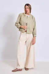 Cazadora corta color verde militar, con cuello redondo, cierre frontal de botones y mangas largas con puños elásticos.