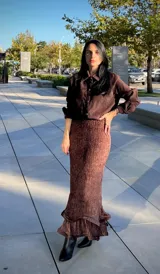 Falda larga de corte sirena en color marrón, confeccionada en tejido con textura plisada y terminación de volado en el ruedo.