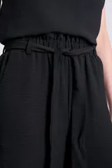 Pantalón negro de corte palazzo con lazo en la cintura y textura arrugada.