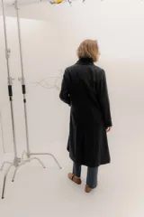 Tapado largo de corte recto y estilo minimalista, confeccionado en tela de color negro. Presenta solapas amplias, bolsillos frontales de parche y un diseño abierto que permite superponer capas.