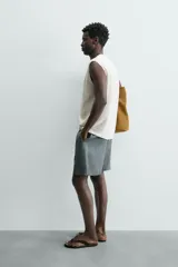 Bermuda de lino color blanco hueso, de corte relajado y tiro medio. Presenta cintura elástica ajustable con cordón, pliegues frontales y bolsillos laterales y trasero.