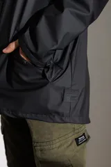 Campera impermeable verde con capucha, cierre frontal con botones a presión y bolsillos laterales con solapa.