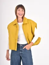 Chaleco acolchado de corte holgado, color mostaza, con cuello camisero y cierre frontal completo.
