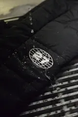 Pantalón negro acolchado con cintura elástica, bolsillos con cierre y logo estampado en la pierna.